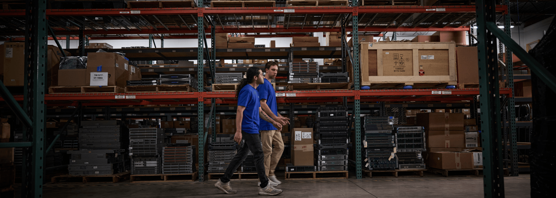 Two men walking through an aisle in an IT asset warehouse.